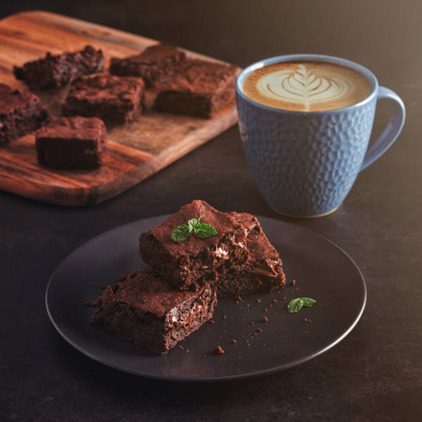 Brownies with Latte art coffee on dark table and wooden cutting board