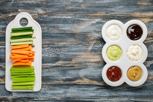 Set of different sauces - ketchup, mayonnaise, barbecue,  teriyaki, mustard, pesto, adzhika and Crudites  on dark background. Top view. Flat lay. Copy space