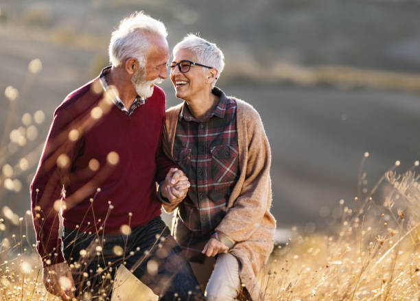 feliz pareja mayor hablando mientras camina en una colina en el día de otoño. - senior adult fun autumn senior couple fotografías e imágenes de stock