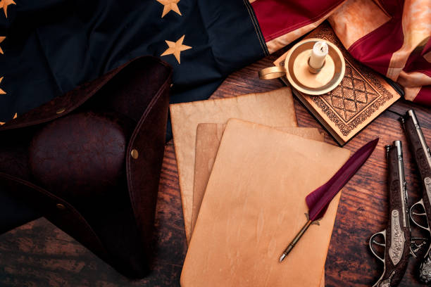 federalist papers and the birth of the united states of america concept with tricorn hat, candle, feather quill, musket gun, the betsy ross american flag and aged paper with copy space - colony imagens e fotografias de stock