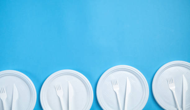 istock White plastic plates, forks and knifes on blue background. 1220062636