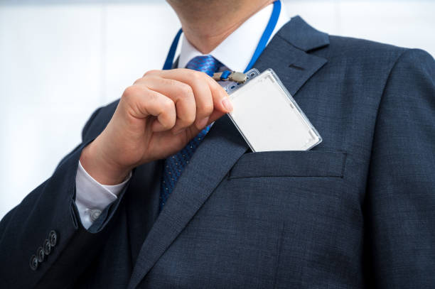 Businessman in suit wearing a blank ID tag or name card on a lanyard at an exhibition or conference. stock photo