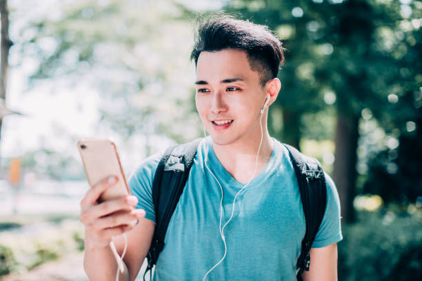 istock happy young man  walking on street and using mobile phone 1220066684