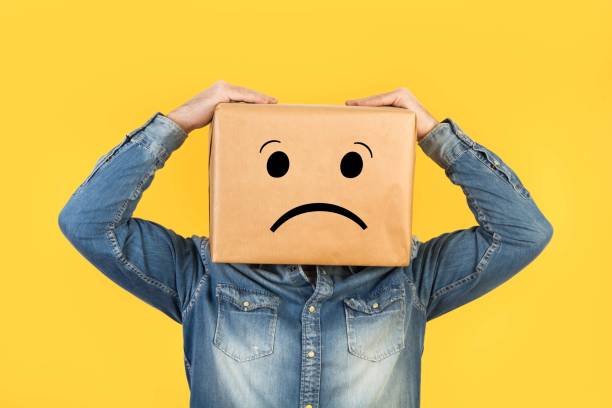 istock Man with his head in a box and sadness gesture drawn on it 1220067007