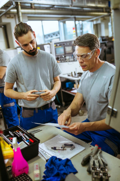 istock Senior male inspector doing quality control with manual worker looking at document 1220067161