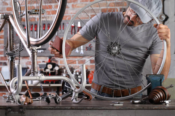 istock man repair the vintage bicycle in garage workshop on the workbench with tools, remove the rust with sand paper, diy concept 1220067269