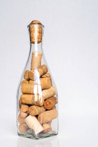 a transparent bottle full of wine corks on white background. concept of heavy drinking - wine bottle wine wood bottle stopper imagens e fotografias de stock