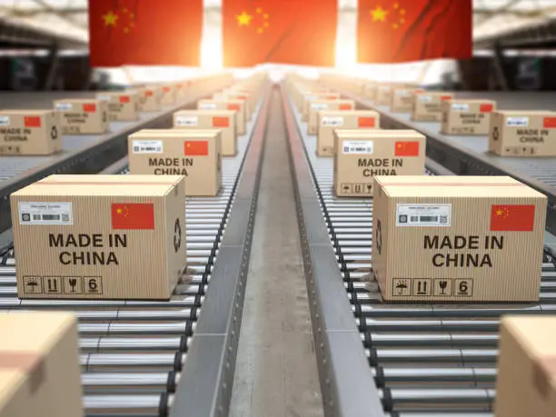 Photo of Made in China. Cardboard boxes with text made in China and chinese flag on the roller conveyor.