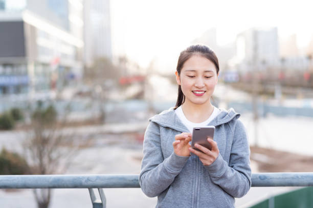 istock Asian young woman using mobile phone in city public square 1220069683