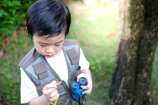 istock Curious little young Asian boy holding a binoculars and cicada molt in the garden. Exploring the world 1220071242