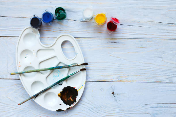 istock Paint palette with tassels and paints on a light blue wooden background. Flat lay art tools. Artwork workplace 1220071984