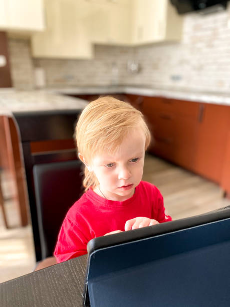 istock A fair-skinned little child sitting at a table in the kitchen, self-learning using a tablet. 1220073525