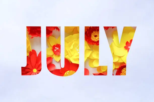 Photo of The lettering july, made of paper flowers. Hello, july. Concept of flowering, summer