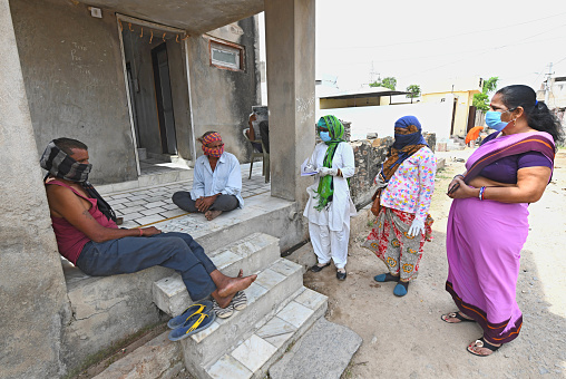 Beawar, Rajasthan, India - April 20, 2020: Anganwadi workers wearing protective face mask interacts with people during a door-to-door survey to check the spread of novel coronavirus, at slum area in Beawar.