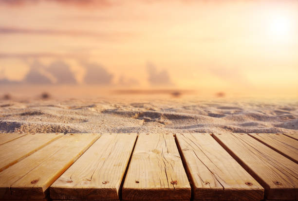 istock Empty wooden plank beside sand beach with sunset sky background 1220075593