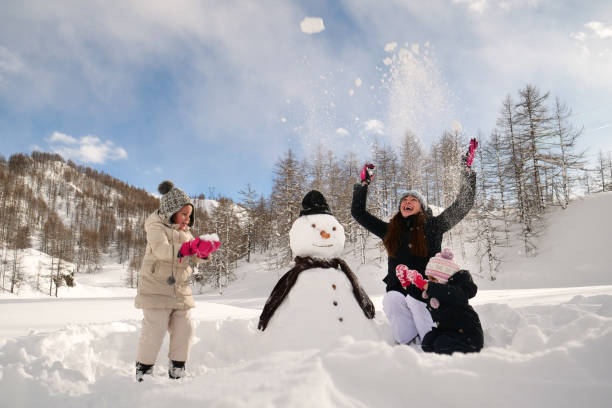 an einem wintertag, in den bergen mit schnee, spielt eine familie den schneemann zusammen - father directly below child looking up stock-fotos und bilder