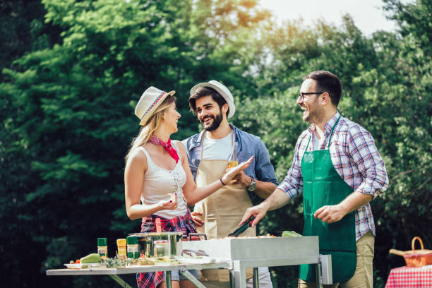 istock Group of people standing around grill, chatting, drinking and eating. 1220080415