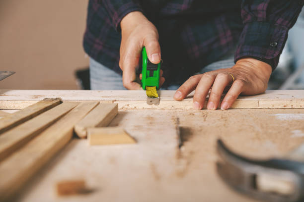 istock Carpenter holding a measure tape on the work bench.Construction industry, do it yourself. Wooden work table. 1220081641