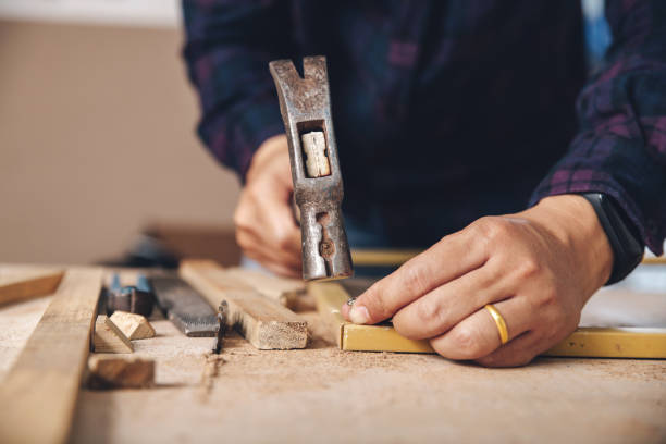istock Carpenter hammer a nail. Construction industry, do it yourself. Wooden work table. 1220081644