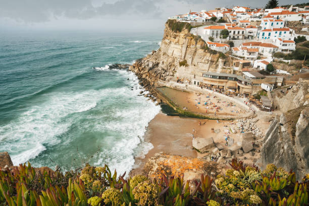 portugal linda ciudad azenhas do mar. olas del océano atlántico rodando a la pequeña playa. las casas de tiza blanca se construyen sobre un borde de acantilado. sintra landmark, europa - azenhas do mar fotografías e imágenes de stock