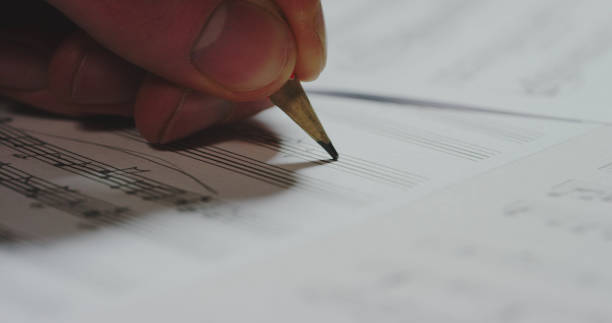 istock Macro close up of musician or composer hand writes a song or a musical work, writing notes with pencil on the pentagram 1220083077