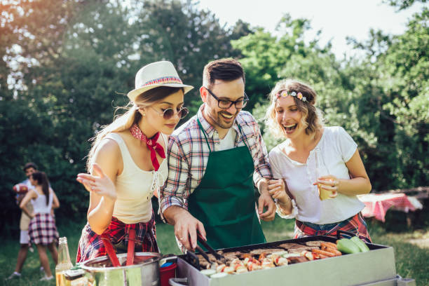 istock Group of people standing around grill, chatting, drinking and eating. 1220083316