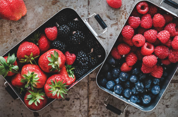 istock Flat-lay of fresh berries in metal lunchboxes over grey background 1220084727