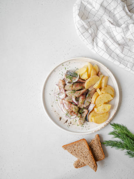istock Marinated Herring fish with potatoes slices and red onion, rye bread on the white table. Top view 1220085198