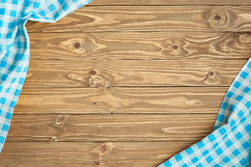 Blue checkered tablecloth on wooden table. Background with copy space. Horizontal.