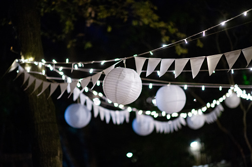 Chinese Lanterns with bunting and hanging fairy lights  at night in a forest