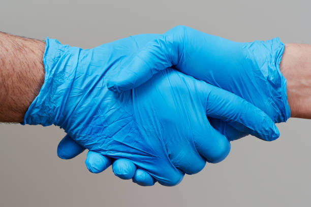 istock two people shaking hands wearing surgical gloves 1220089137