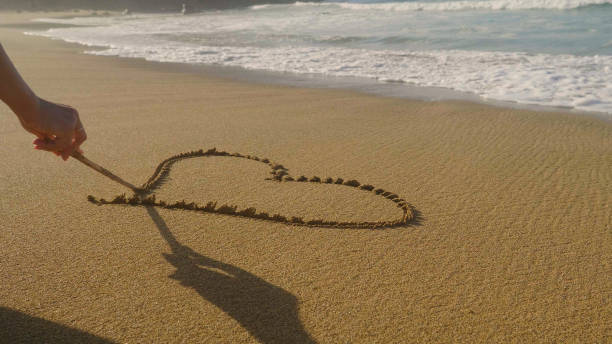 istock Beautiful painted heart on brown sand, sunset, sea background. 1220090829