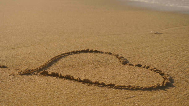 istock Beautiful painted heart on brown sand, sunset, sea background. 1220091229