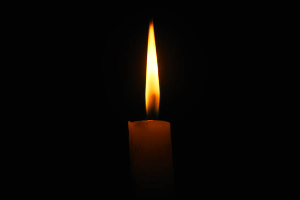 istock Lit flame of a candle on dark background 1220093644