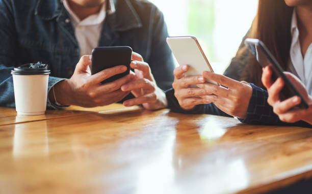istock Group of people using and looking at mobile phone together 1220093859