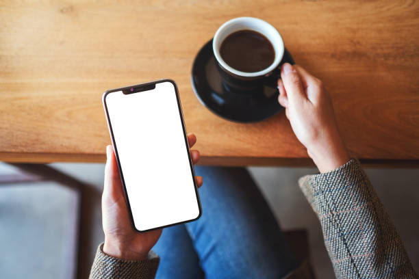 istock a woman holding black mobile phone with blank desktop screen while sitting in cafe 1220093880