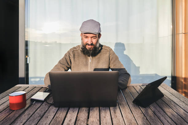 istock middle-aged man teleworking with his laptop from his rooftop during coronavirus isolation 1220095542
