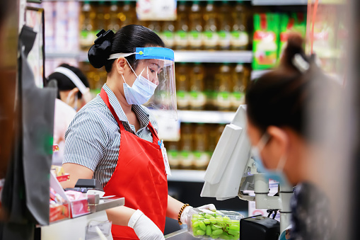 cajera de supermercado femenino en máscara de protección médica que trabaja en el supermercado photo