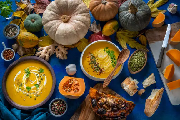 Autumn pumpkin soup and ingredients on dark blue table