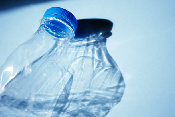 istock Transparent empty plastic bottle for ecological recycled backlit by bright sunlight on a colored blue background 1220096181
