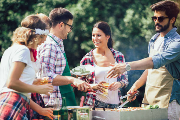 istock Group of people standing around grill, chatting, drinking and eating. 1220099214