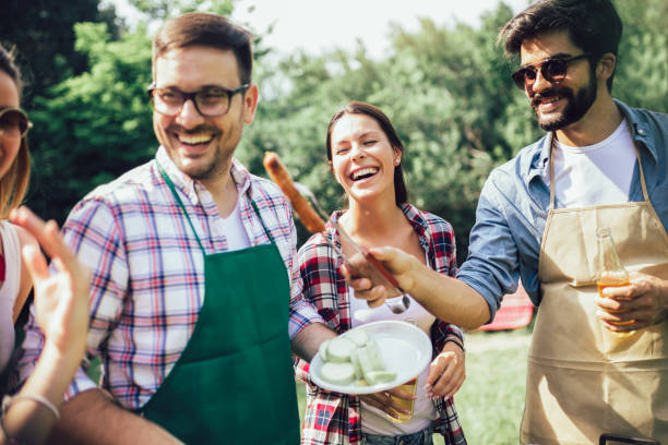 istock Group of people standing around grill, chatting, drinking and eating. 1220099471