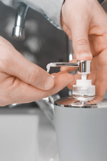 istock Hand washing concept: man in shirt soap his hands through a soap dispenser 1220100837
