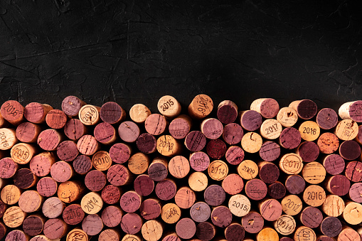 Wine corks background, a design template for a restaurant menu or winery brochure, shot from above with copy space, on a black background