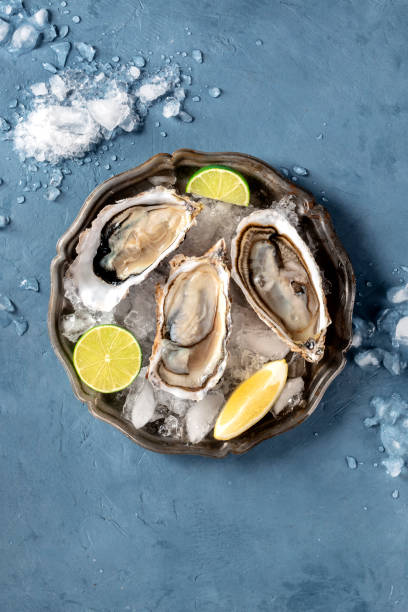 istock Oysters on ice, overhead shot on a slate, with lemon and lime 1220103504