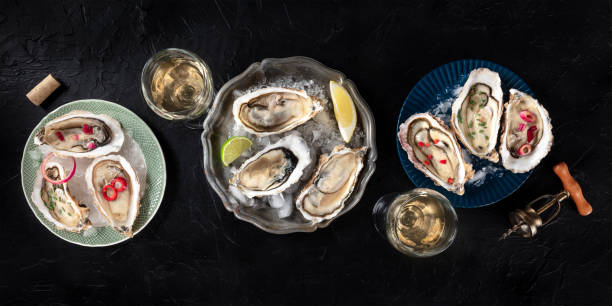 Oysters with various toppings panorama, shot from above with wine, with lemon and lime, pepper, onion, on a dark background