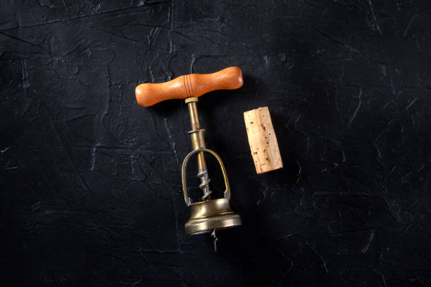 istock Wine tasting concept. A vintage corkscrew and a cork, shot from the top on a black background 1220103921