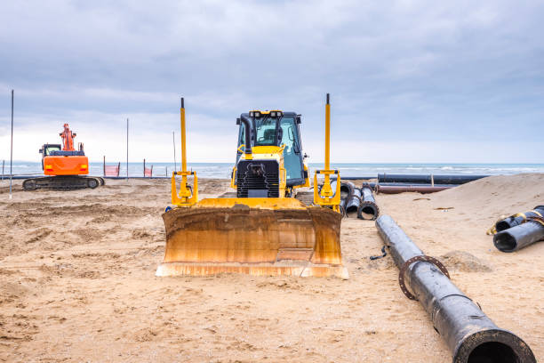 istock Two construction machines excavator sandandands and wheel loaders with sewer pipe 1220103929