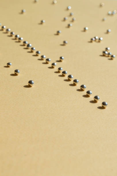 istock Rows of silver bakery beads with sunny shadows. Vertical photo with empty space down for necessary use. Geometry lines of sugar pearls on the light yellow background. Trendy concept idea 1220104855