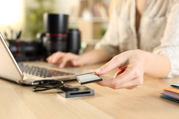 Photographer hands plugging memory card to laptop Close up of photographer woman hands plugging memory card to laptop on a desk at home usb port photos stock pictures, royalty-free photos & images